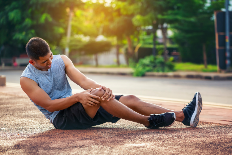 Athlete clutching knee in pain from ACL injury outdoors